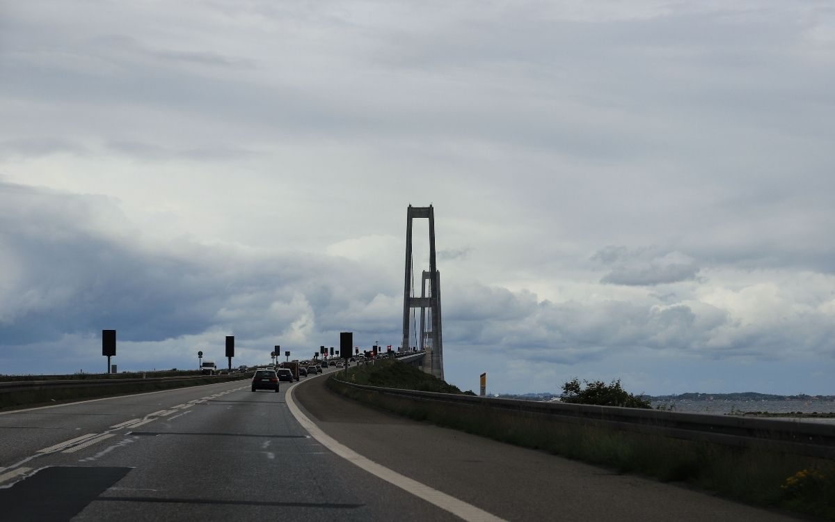 Mit dem Auto auf die Pylone der Große-Belt-Brücke zu unter bewölktem Himmel